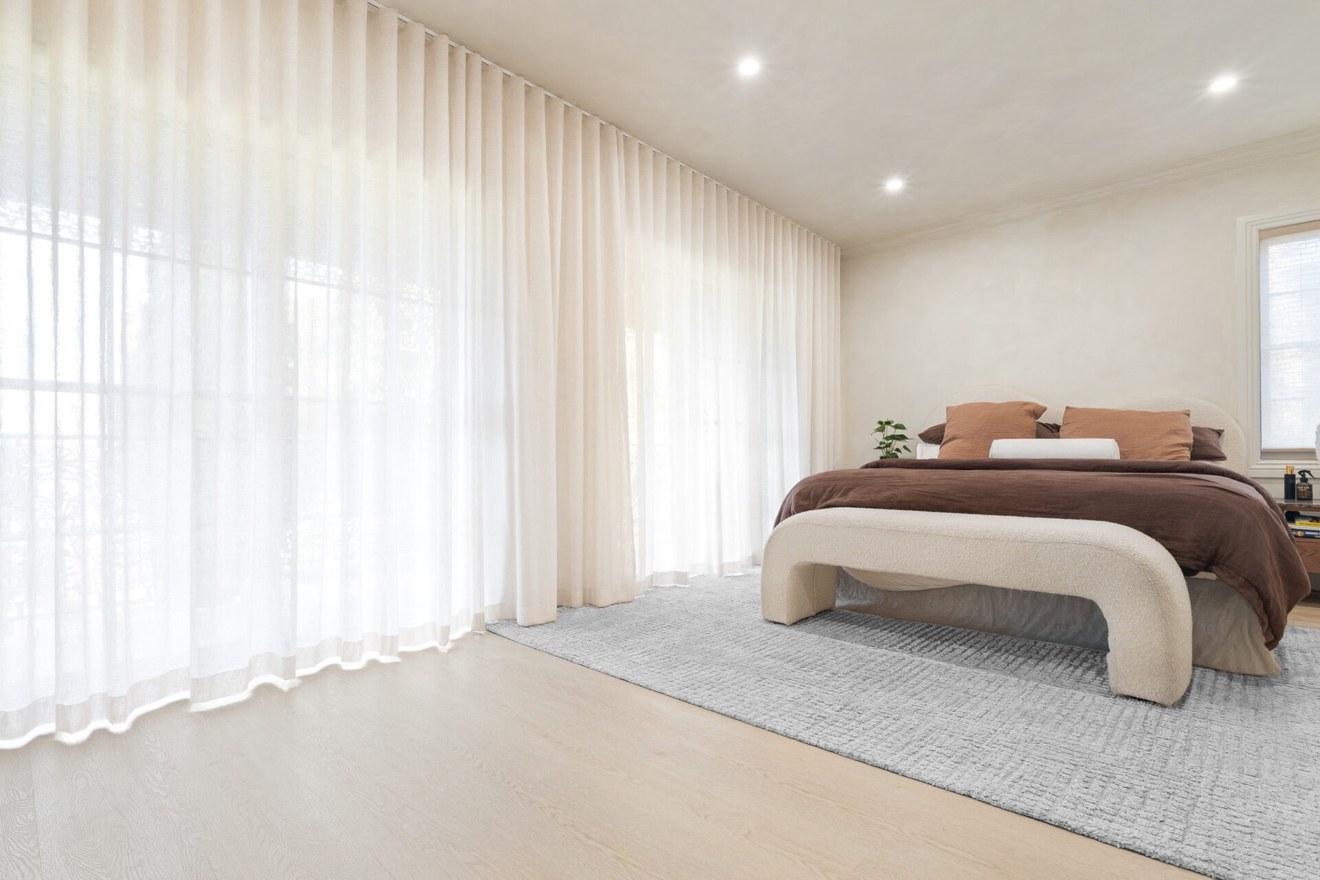 Alpine Beech hybrid flooring in a bright bedroom with sheer floor-to-ceiling curtains