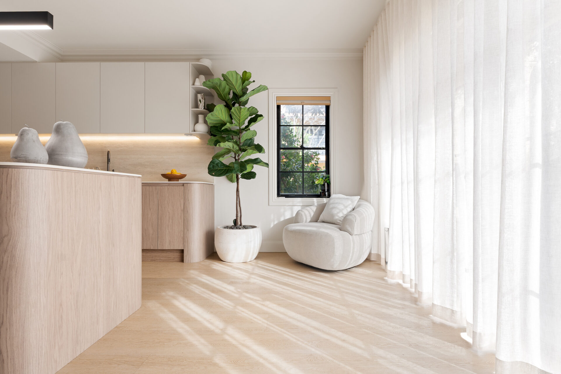 Alpine Beech hybrid flooring in a bright kitchen corner with a fluted timber island and sheer curtains