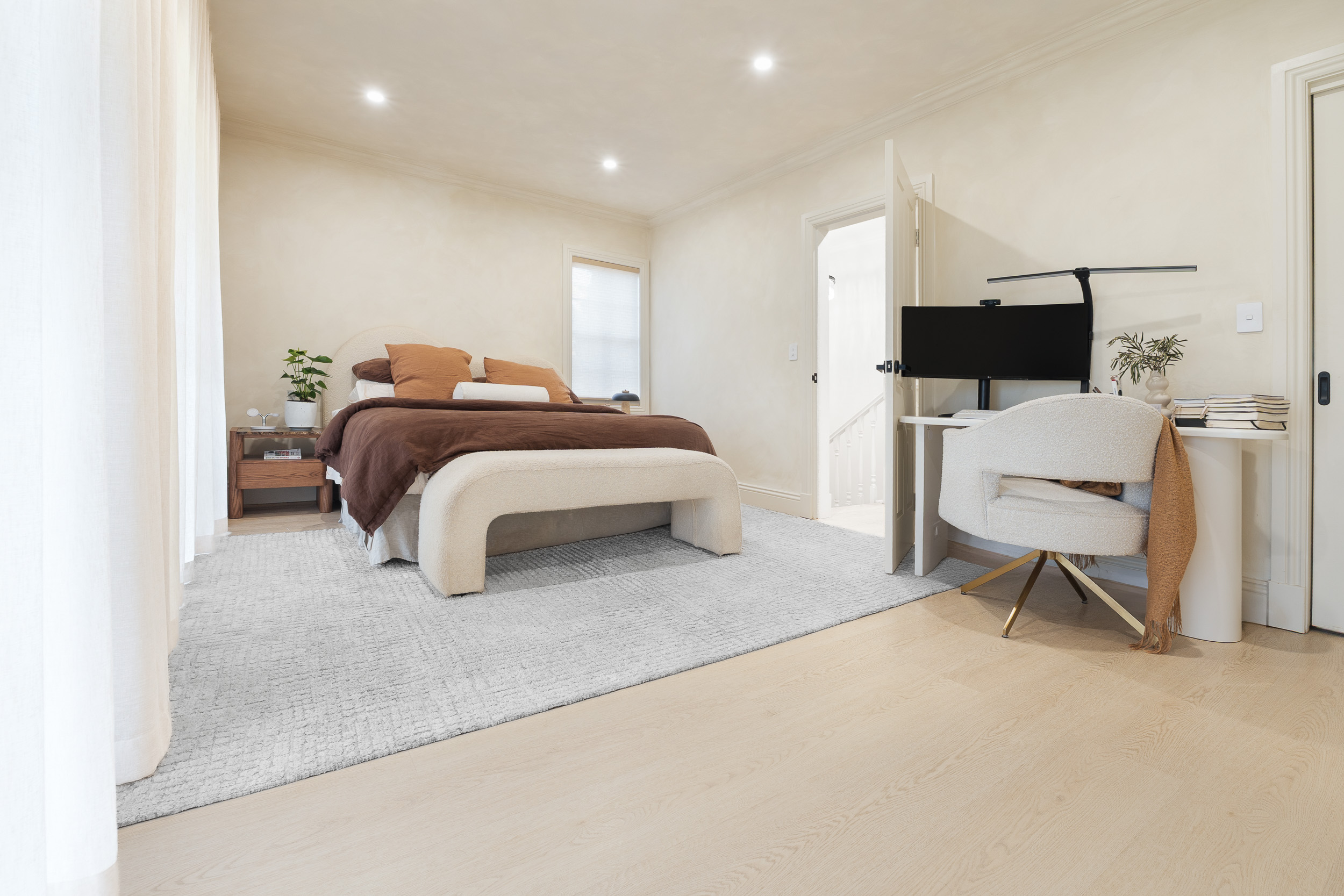 Alpine Beech hybrid flooring in a master bedroom with a rug and upholstered bed