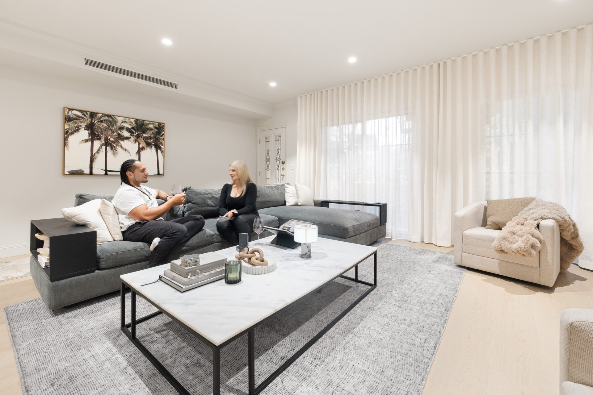 Alpine Beech hybrid flooring in a living room with a grey sectional sofa and marble coffee table