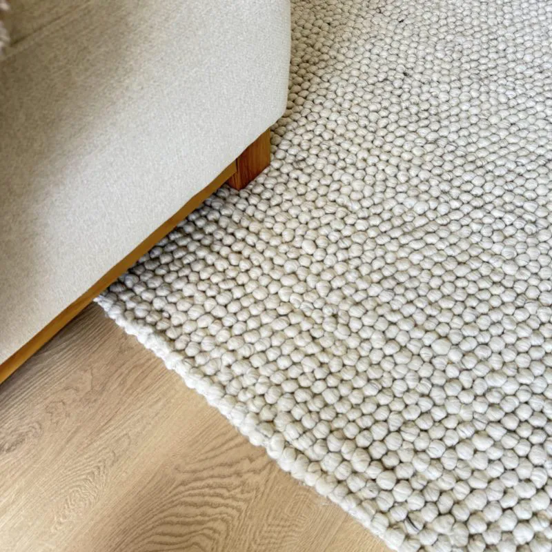 Beige oak flooring featured alongside textured cream rug available now from Beare Flooring