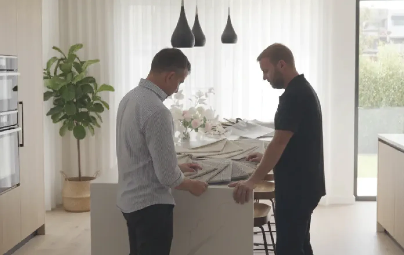Beare Flooring consultant showing carpet samples to customer in modern kitchen.